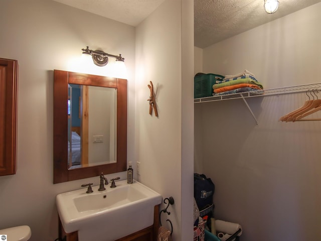 bathroom with toilet, sink, and a textured ceiling