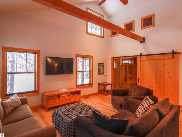 living room featuring ceiling fan, a barn door, high vaulted ceiling, and light wood-type flooring