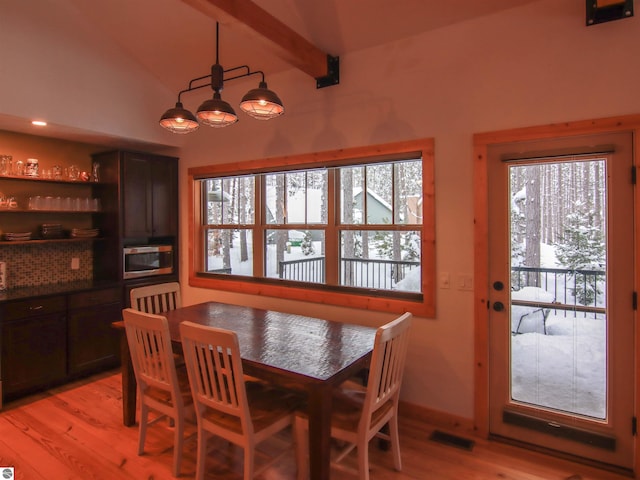 dining room with vaulted ceiling with beams and light wood-type flooring