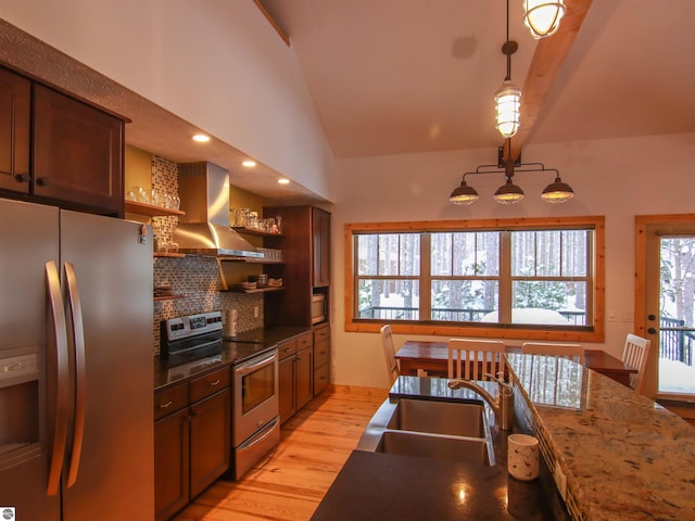 kitchen with lofted ceiling, sink, appliances with stainless steel finishes, range hood, and decorative light fixtures