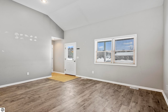 spare room with wood-type flooring and lofted ceiling