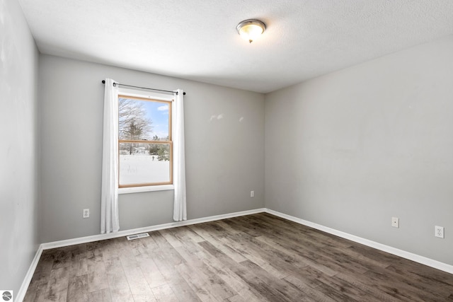 spare room featuring hardwood / wood-style flooring and a textured ceiling