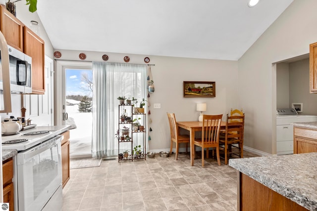 kitchen featuring white electric stove, separate washer and dryer, and vaulted ceiling