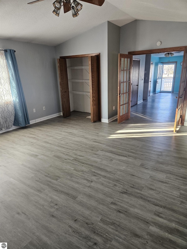 unfurnished bedroom with vaulted ceiling, dark hardwood / wood-style floors, ceiling fan, and a textured ceiling