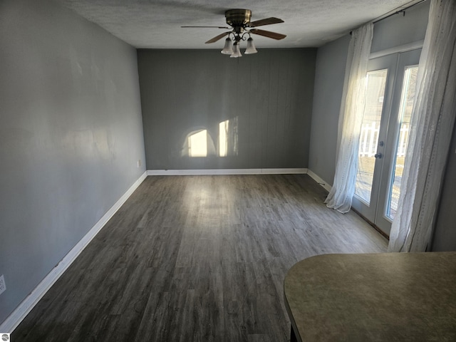 empty room with ceiling fan, dark hardwood / wood-style floors, a textured ceiling, and french doors