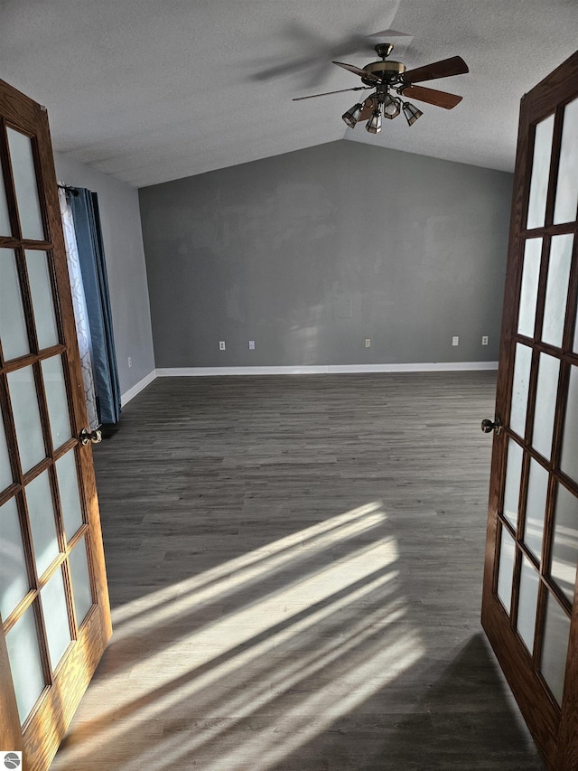 spare room with vaulted ceiling, dark hardwood / wood-style floors, a textured ceiling, and french doors