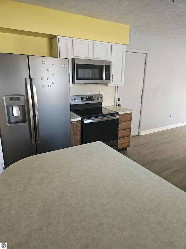 kitchen featuring white cabinetry, dark hardwood / wood-style floors, a textured ceiling, and appliances with stainless steel finishes