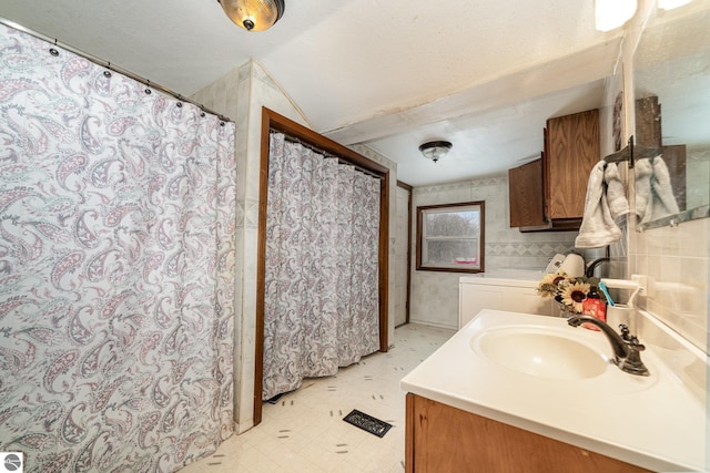 bathroom featuring independent washer and dryer, vanity, and a textured ceiling