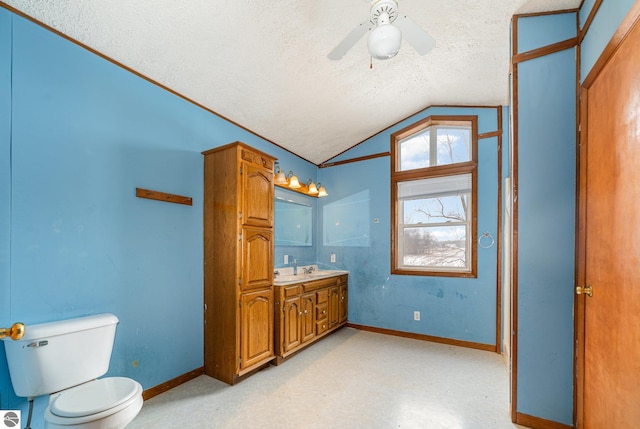 bathroom featuring lofted ceiling, toilet, a textured ceiling, vanity, and ceiling fan