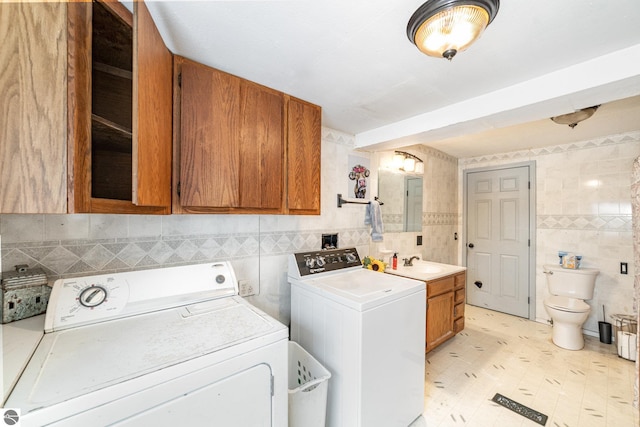 laundry area featuring washing machine and clothes dryer, sink, and tile walls