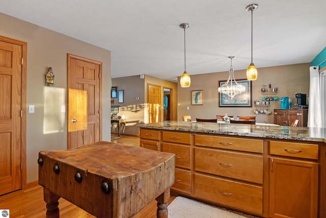 kitchen featuring pendant lighting, light stone counters, and light hardwood / wood-style floors