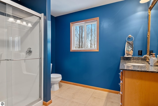 bathroom with a shower with door, vanity, tile patterned floors, and toilet