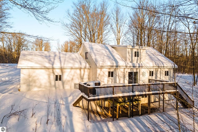 snow covered back of property featuring a deck