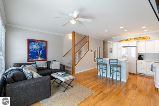 living room with crown molding, ceiling fan, and light hardwood / wood-style flooring