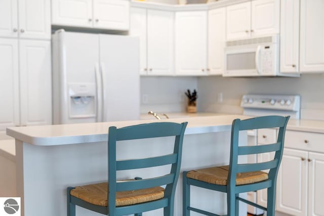 kitchen featuring white cabinetry, white appliances, a kitchen bar, and built in desk