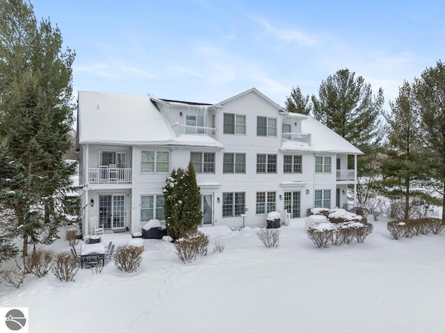 snow covered rear of property featuring a balcony