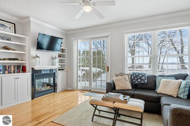 living room with a fireplace, ornamental molding, light hardwood / wood-style floors, and ceiling fan