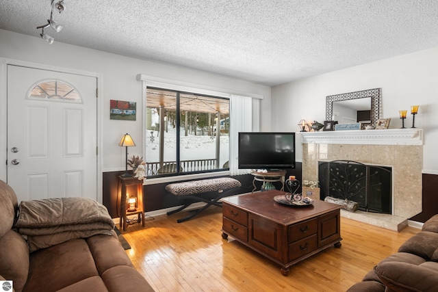 living room featuring light hardwood / wood-style floors, a tile fireplace, and a textured ceiling