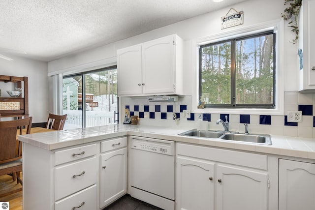 kitchen with sink, tasteful backsplash, dishwasher, kitchen peninsula, and white cabinets