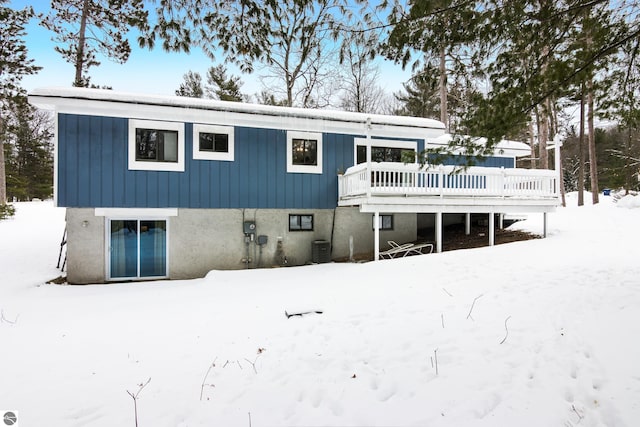 snow covered house featuring central AC unit and a deck