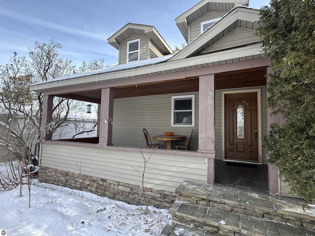 snow covered property entrance with covered porch