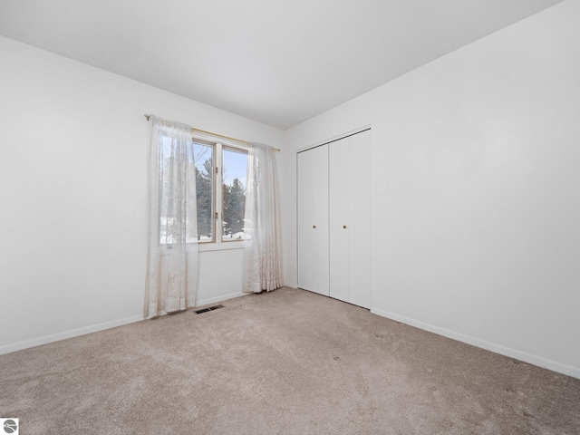 unfurnished bedroom with a closet and light carpet