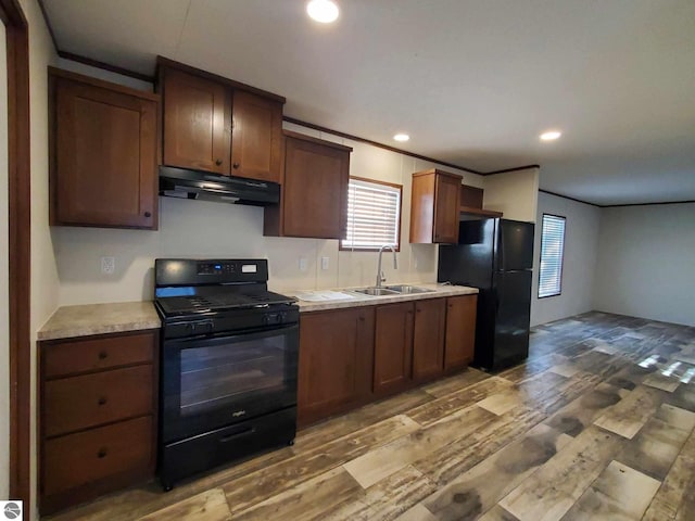 kitchen with dark wood-type flooring, ornamental molding, sink, and black appliances