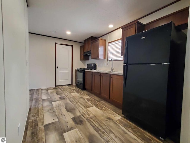 kitchen featuring sink, light hardwood / wood-style flooring, and black appliances