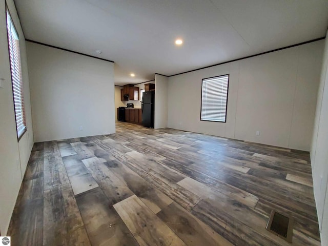 unfurnished living room featuring crown molding and dark wood-type flooring