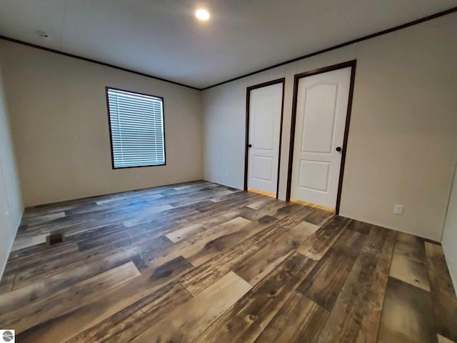 unfurnished bedroom featuring crown molding and dark hardwood / wood-style flooring