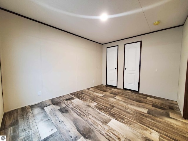 unfurnished bedroom featuring hardwood / wood-style flooring and two closets