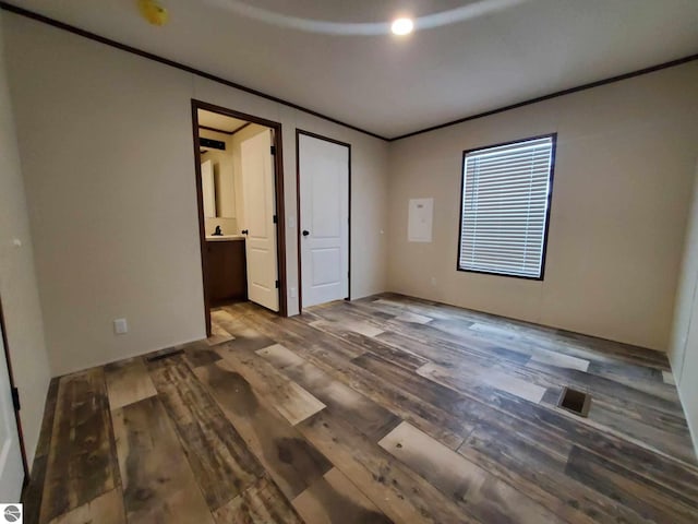 unfurnished bedroom featuring dark hardwood / wood-style flooring and crown molding