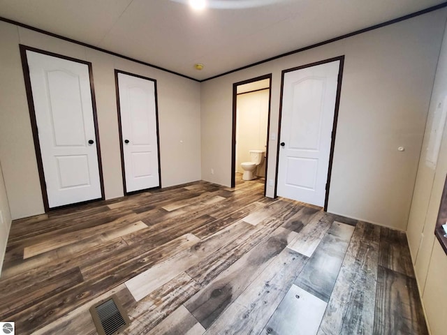 unfurnished bedroom featuring ornamental molding, wood-type flooring, and ensuite bathroom