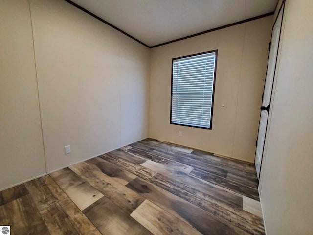 spare room with ornamental molding and dark hardwood / wood-style floors