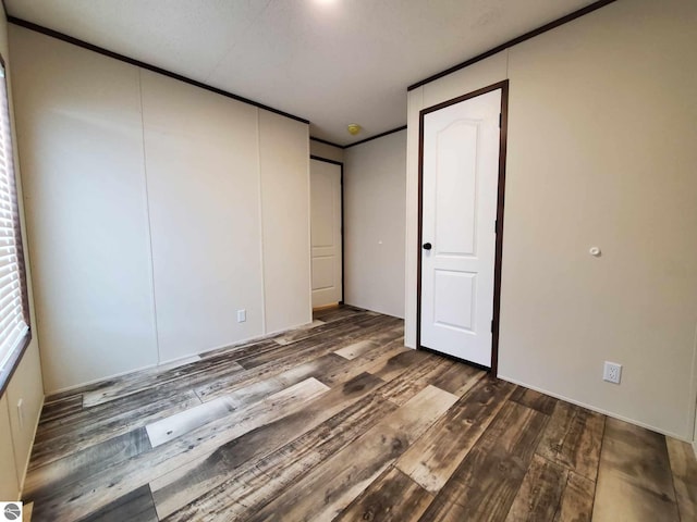 unfurnished bedroom featuring ornamental molding, dark hardwood / wood-style flooring, and a closet