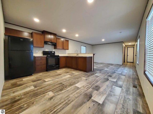 kitchen featuring sink, kitchen peninsula, light wood-type flooring, and black appliances