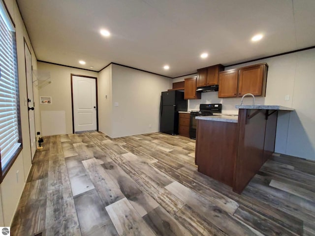 kitchen featuring sink, hardwood / wood-style flooring, ornamental molding, black appliances, and kitchen peninsula