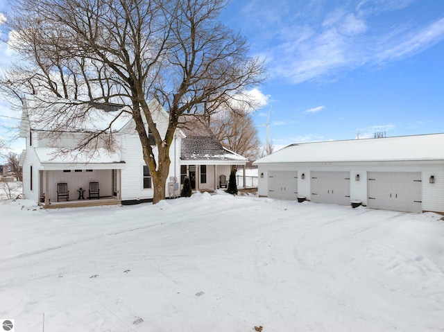 snow covered property with a garage and covered porch