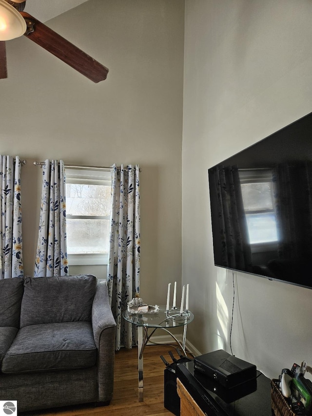 living room with hardwood / wood-style flooring, ceiling fan, and a high ceiling