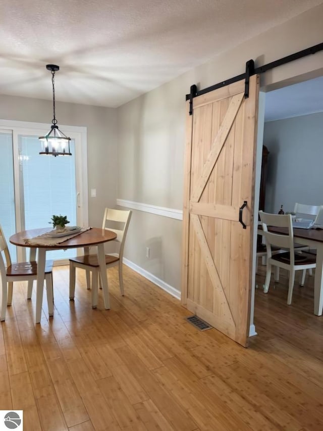 dining space featuring wood-type flooring, a barn door, and a textured ceiling