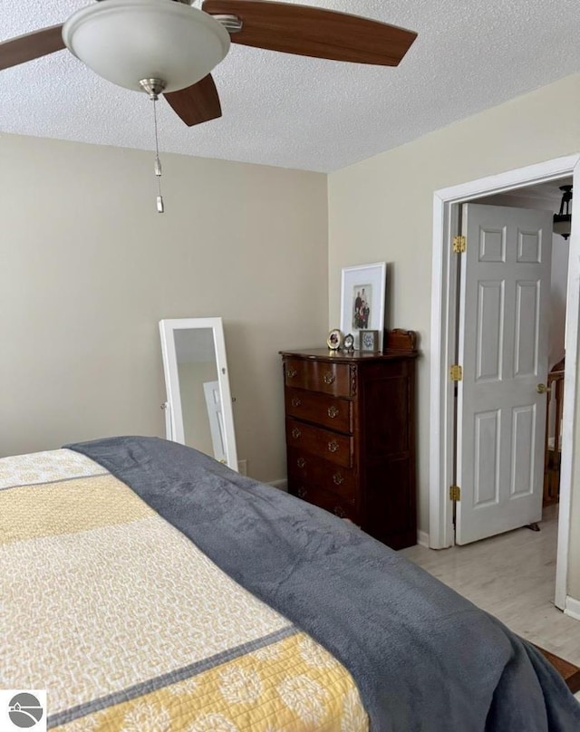 bedroom with ceiling fan, light hardwood / wood-style flooring, and a textured ceiling