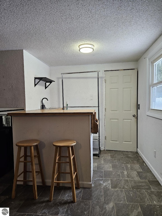 kitchen with a breakfast bar, a textured ceiling, and kitchen peninsula