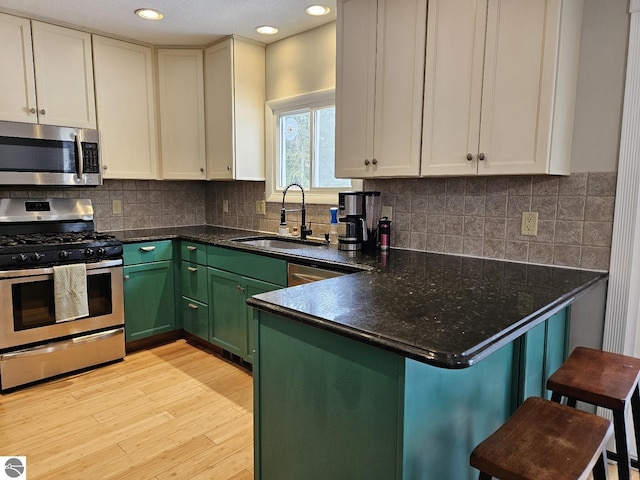 kitchen with sink, a kitchen breakfast bar, kitchen peninsula, and appliances with stainless steel finishes