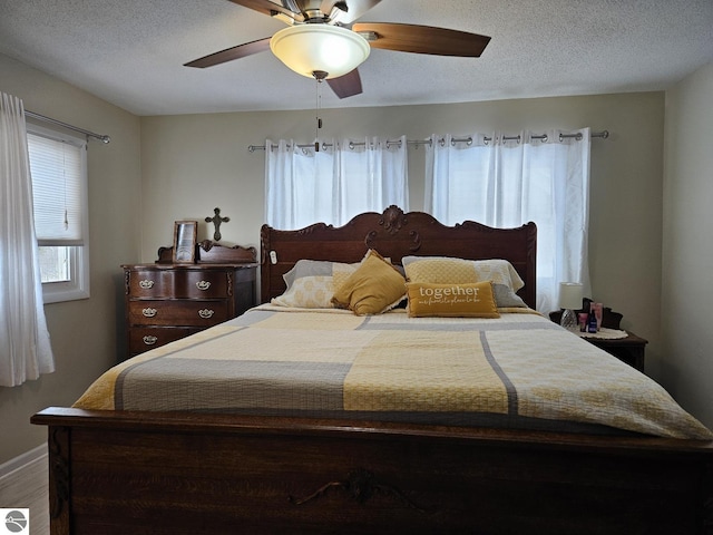 bedroom with ceiling fan, wood-type flooring, and a textured ceiling