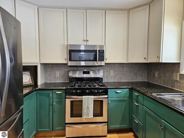 kitchen with dark stone countertops, decorative backsplash, white cabinets, and appliances with stainless steel finishes