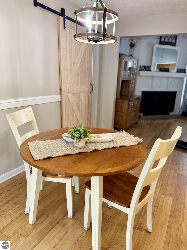 dining room featuring hardwood / wood-style flooring, a barn door, and an inviting chandelier