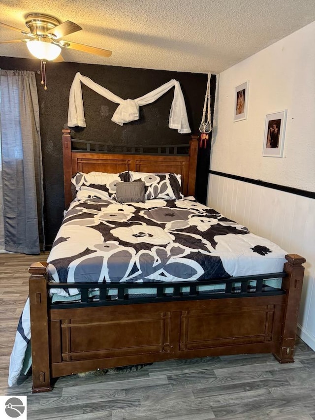 bedroom featuring ceiling fan, dark wood-type flooring, and a textured ceiling