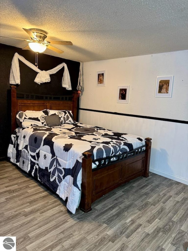 bedroom with hardwood / wood-style flooring, ceiling fan, and a textured ceiling