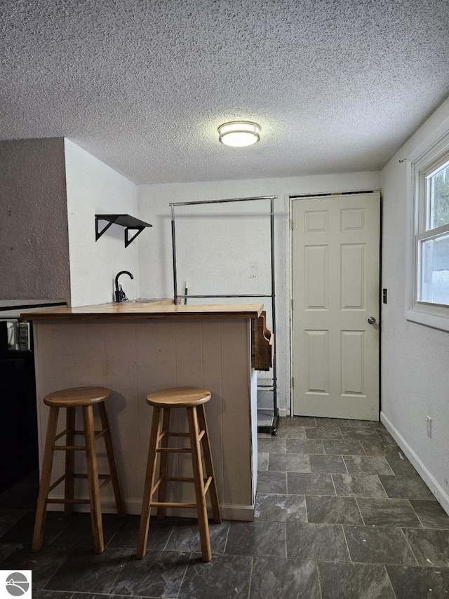 kitchen with a textured ceiling, a breakfast bar, and kitchen peninsula