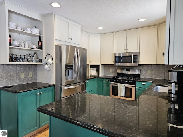 kitchen featuring stainless steel appliances, green cabinets, dark stone countertops, and kitchen peninsula